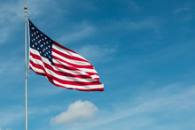 American Flag Against The Backdrop Of A Blue Sky And Clouds.  