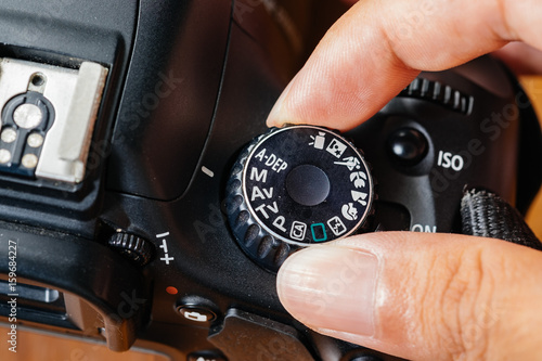 Fotomural Manual dial mode on dslr camera with fingers on the dial