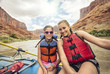 © Brocreative - Active young family enjoying a day rafting down a whitewater river together. The mother and daughter sitting together on a large raft floating down a red rock canyon