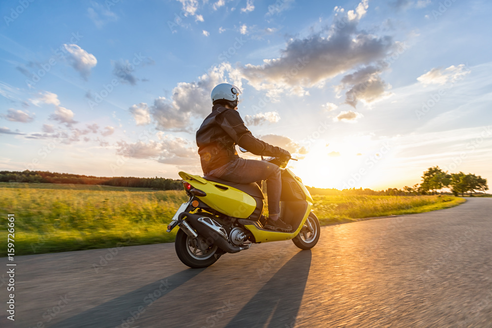 Motorbiker riding on empty road with sunset sky - obrazy, fototapety, plakaty 