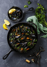 Mussels In Black Cooking Pan With Parsley On Dark Stone Background