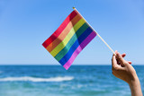 Fototapeta Tęcza - man waving a small rainbow flag