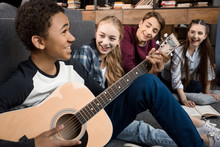African American Boy Playing Acustic Guitar And Singing While His Friends Listening At Home, Teenagers Playing Guitar Concept