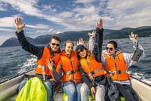 Portrait Of Young And Attractive People, Friends In The Motorboat Driving Somewhere On A Picnic. Happy Faces, Having Fun, Norway. Raised Up Hands.