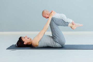 Wall Mural - young mother does physical yoga exercises together with her baby boy