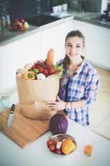 Wall Mural - Young woman holding grocery shopping bag with vegetables .