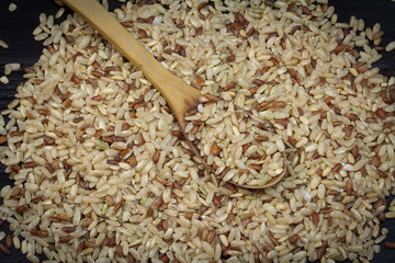 Integrated brown rice spilled on the wooden background