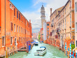 Motor boat in beautiful canal with old Bell tower, Venice