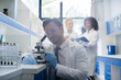 © mast3r - Male Scientist Working With Microscope, Team In Laboratory Doing Research, Man And Woman Making Scientific Experiments Doctors In Lab