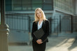 © Alexandr - Smiling beautiful young girl with blond hair in a black suit, in the courtyard of a modern building