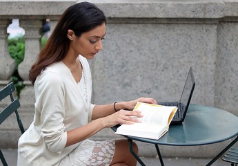 Young attractive woman reading while sitting outside in urban park