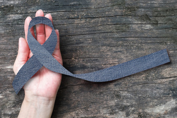 Sticker - Blue jeans denim ribbon (isolated with clipping path) on helping hand support and aged wood for genetic disorder awareness and children's rare disease illness 