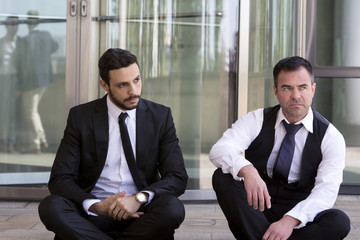 two businessmen sitting outside and looking serious