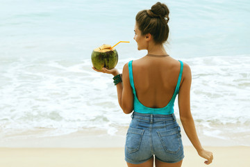 Wall Mural - Woman with a coconut drink on the beach