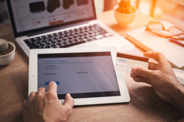 Young man shopping online at home on laptop computer, Hand holding digital tablet with Payment Detail page display and credit card, online shopping concepts