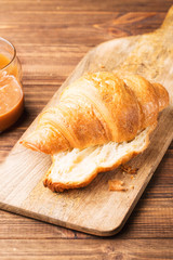 Fresh croissants with salted caramel on a brown wooden background, closeup, vertical, selective focus
