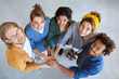 © wayhome.studio  - View from above of five multiracial people standing together stacking their hands looking happily symbolyzing their friendship and support. International fellowship. Mixed race people community