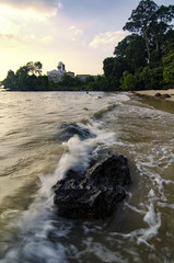 Wall Mural - soft wave flow hitting the sandy beach over cloudy sky background. soft focus image due to long exposure shot