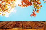 Fototapeta  - Top of wood table with beautiful autumn maple tree on sky background - Empty ready for your product display or montage. Concept of background in fall season
