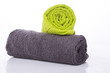 Two towels gray and green twisted into a roll on a white background