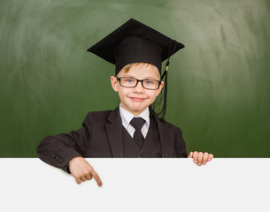 boy in graduation hat pointing at blank white banner
