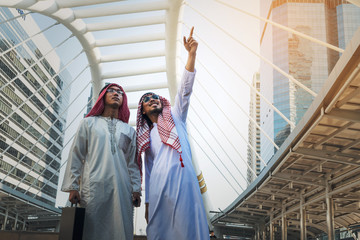 Two Arab businessmen standing by raising both hands up in city, Business good feeling concept