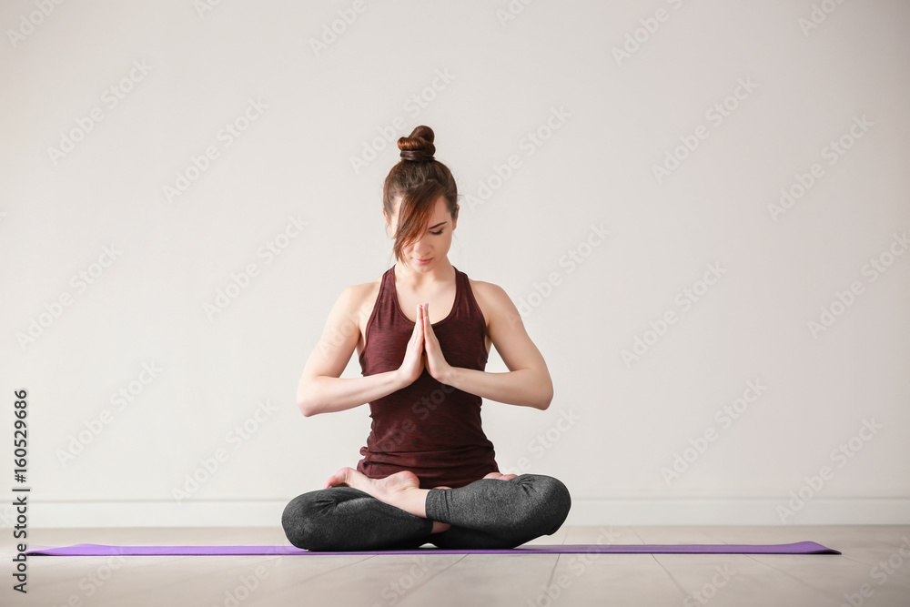 Young woman practicing yoga on light background indoors