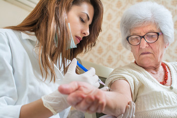 Nurse giving injection to senior woman. Home care.