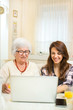 © Bojan - Grandmother and her granddaughter having fun with laptop at home.