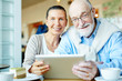 © pressmaster - Affectionate couple of senior spouses spending leisure with touchpad