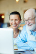 © pressmaster - Mature husband and wife talking through video-chat in cafe