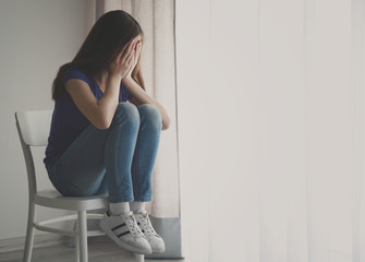 Wall Mural - Cute sad girl near window at home