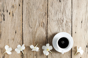 Wall Mural - white coffee cup and frangipani flowers on old wooden table background.