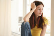 © Africa Studio - Sad pretty girl sitting on window sill at home