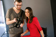 © Photodrive - Photographer communicate with model on photoshoot. Man with camera show pictures to woman in red dress during the studio session. Production of commercials backstage
