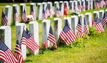 Rows Of Gravestones With Flags In Military Cemetery