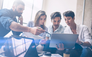 Wall Mural - Teamwork process.Young coworkers work with new startup project in office.Woman holding touch pad in hands,bearded man pointing to screen.Horizontal, blurred, flare.