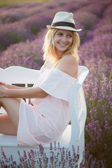 Canvas Print - Happy smiling woman relaxing on beautiful bench in lavender field. 