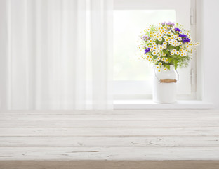 Wooden rustic table in front of wild flowers on windowsill