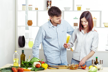 Loving happy couple preparing healthy salad of fresh vegetables in kitchen