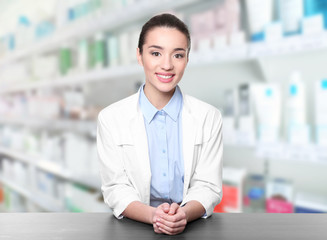 Poster - Young woman pharmacist standing at table on white background