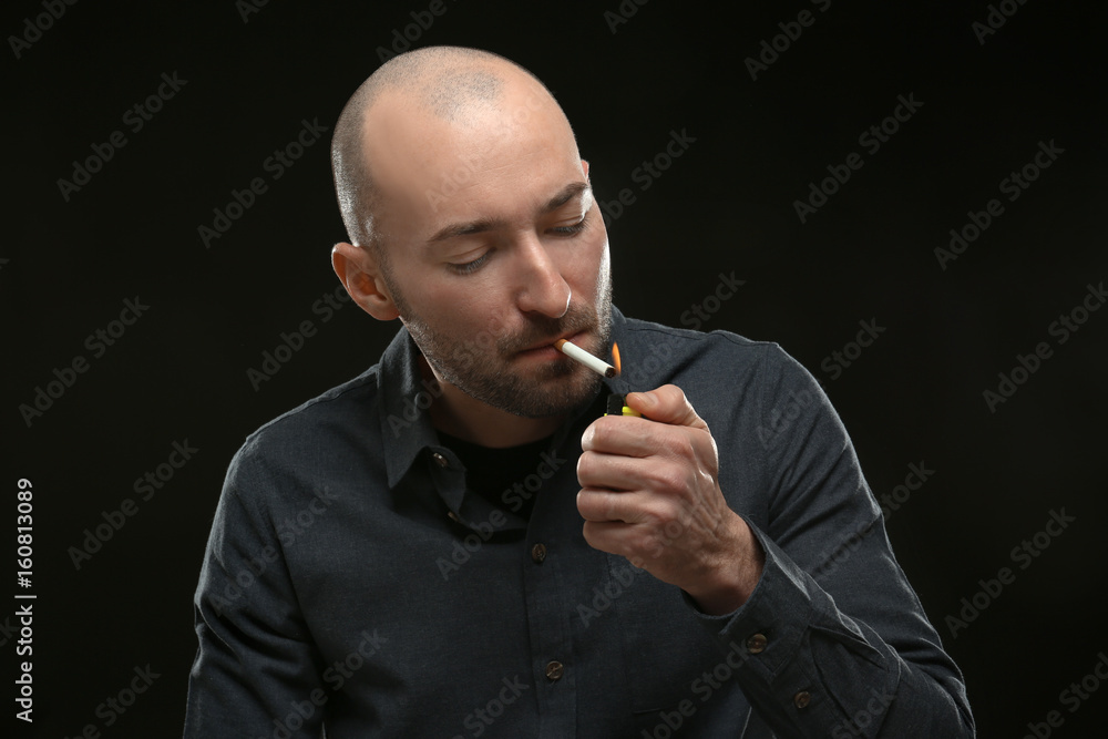 Handsome man smoking cigarette on dark background