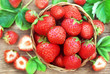 Basket of fresh ripe sweet strawberries on berries and leaves background