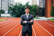 © twinsterphoto - Smiling happy and confident business executive standing with arms folded in performance race track background