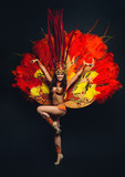 Cute young girl in bright colorful carnival costume on dark background