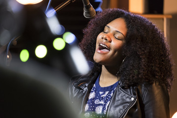 Wall Mural - Black female singing in a recording studio