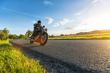 Wall Mural - Dark motorbiker riding high power motorbike in sunset