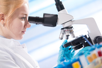 Poster - Doctor woman working  a microscope. Female scientist looking through a microscope in lab. Student girl looking in a microscope, science laboratory concept