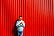 Smiling man with smart phone standing on the backgrond of red wall