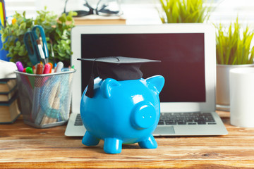 Piggy money box with laptop on wooden table